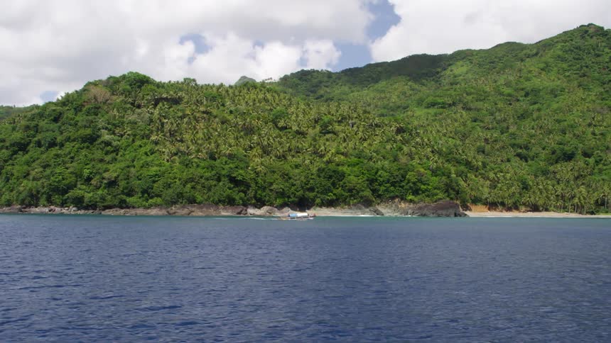 A small boat is moving along the shore ahead