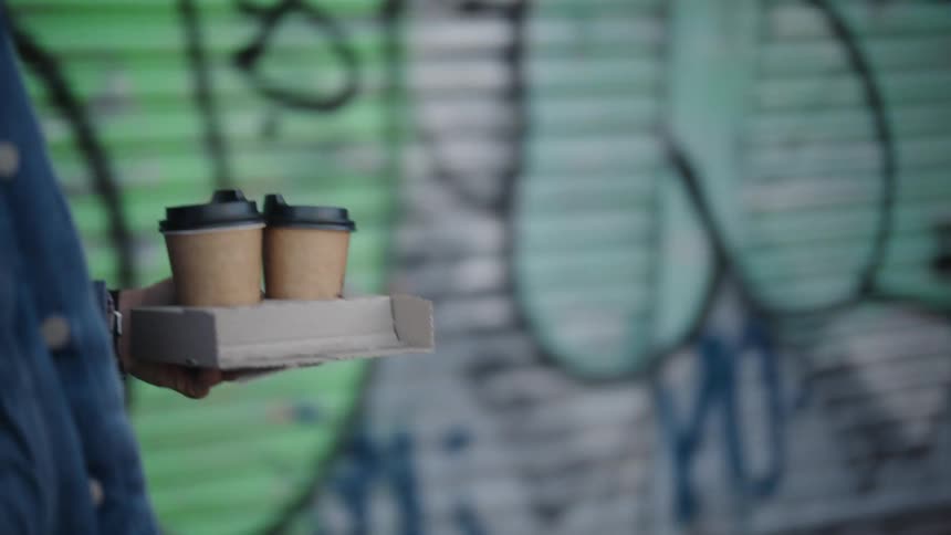 Closeup of a persons hand holding two coffees
