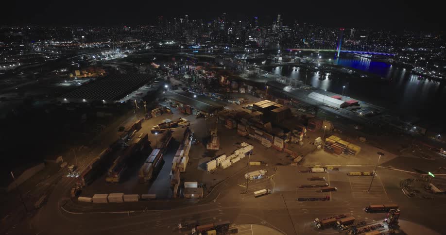 Aerial panorama of a port with containers trucks and the city on the waterfront on a night