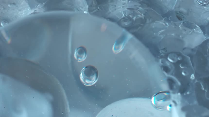 Bubbles float around the edges of ice cube rotating in water