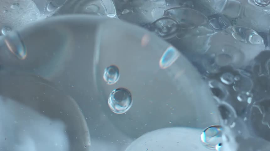 Small bubbles float around the edges of translucent round ice cubes in water