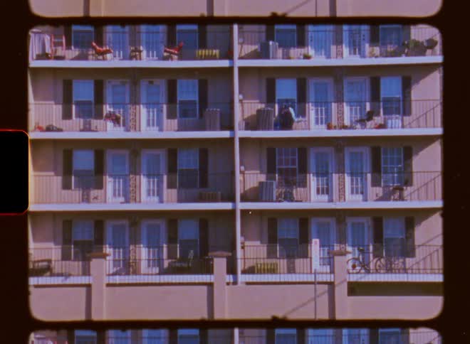 The tall building has many balconies with iron railings