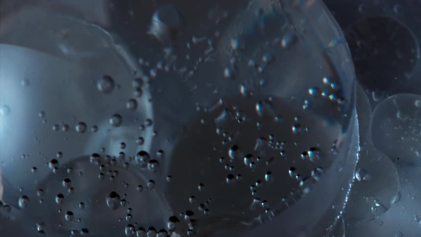 Droplets float among clear spheres as they move in liquid