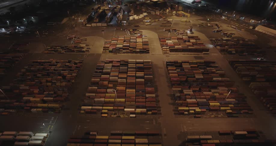 Aerial view of shipping containers and cranes on a port at night