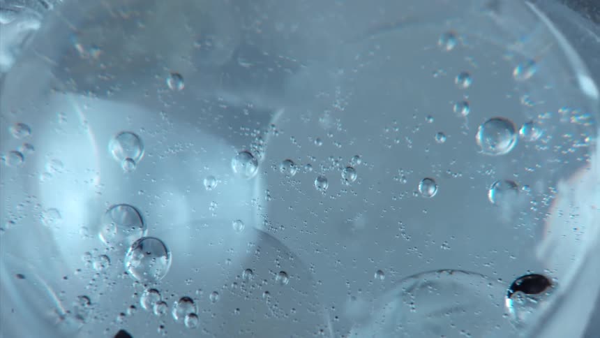 Light shines on bubbles as they float and move inside a clear sphere
