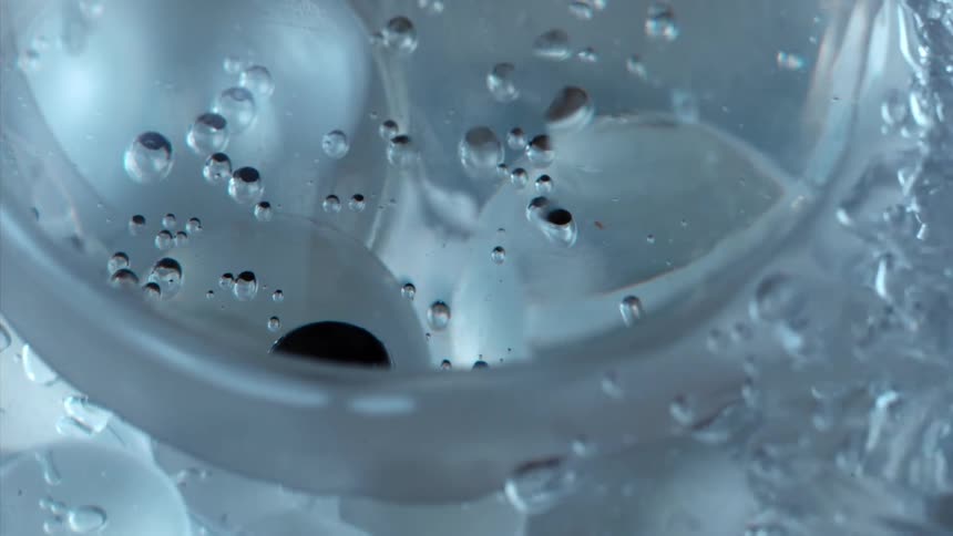Light shines on bubbles as they float and move inside a clear sphere and bubbles move around the outside