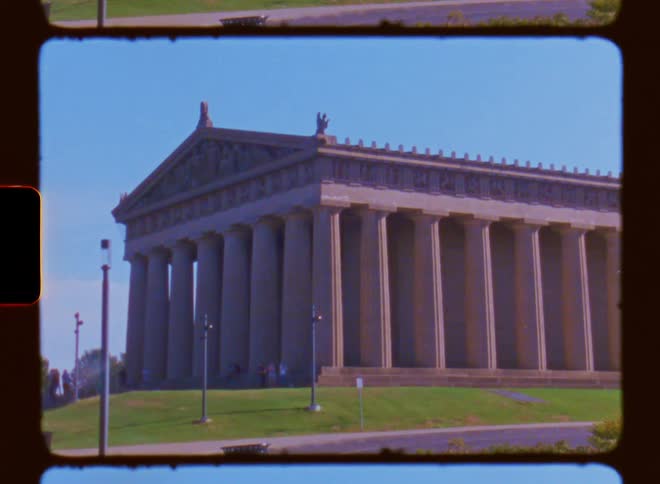 A large stone building is surrounded by pillars