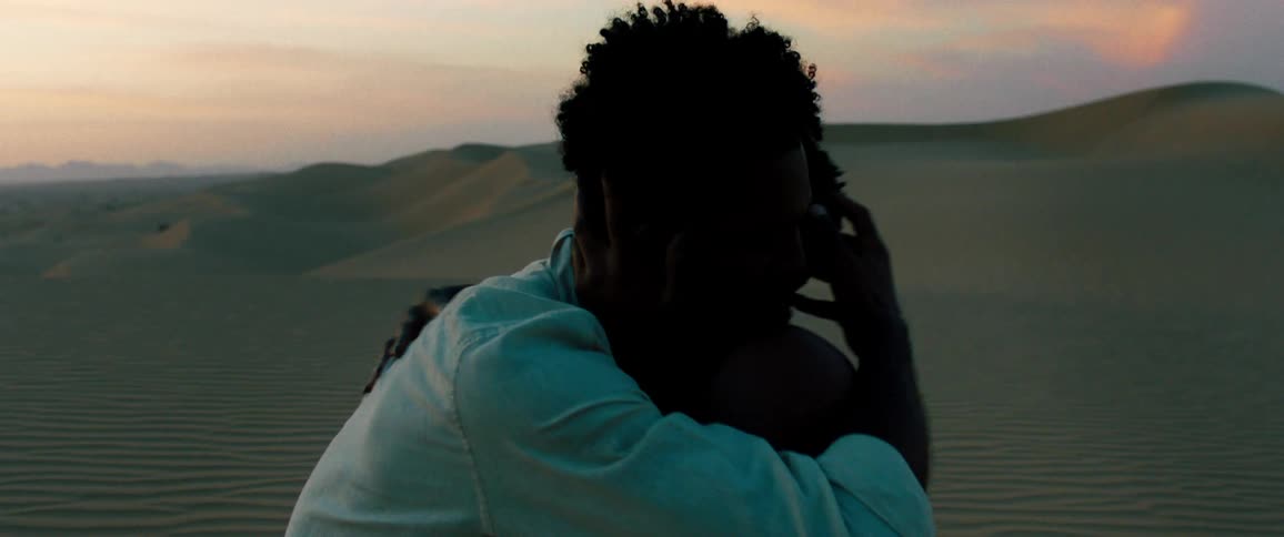 Couple desperately hug and kiss in the desert at sunset