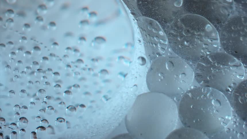 Bubbles are floating and moving in a clear liquid above white spheres