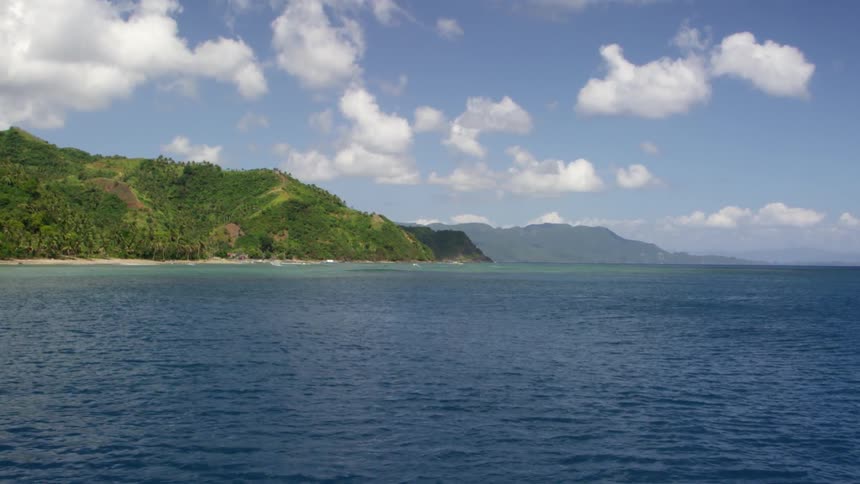 Lake water flows beside tree covered mountains
