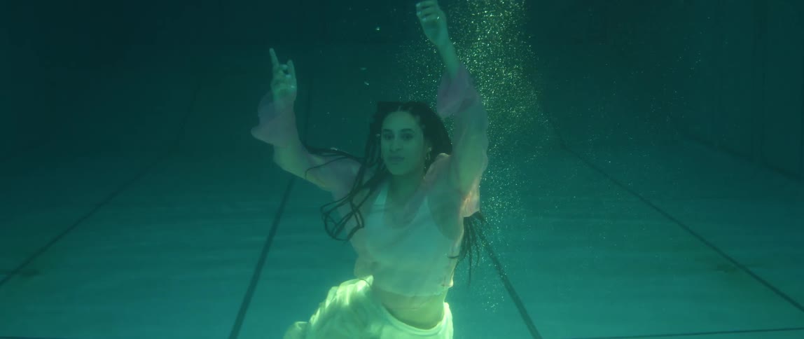 A woman is underwater in a swimming pool moving her body around