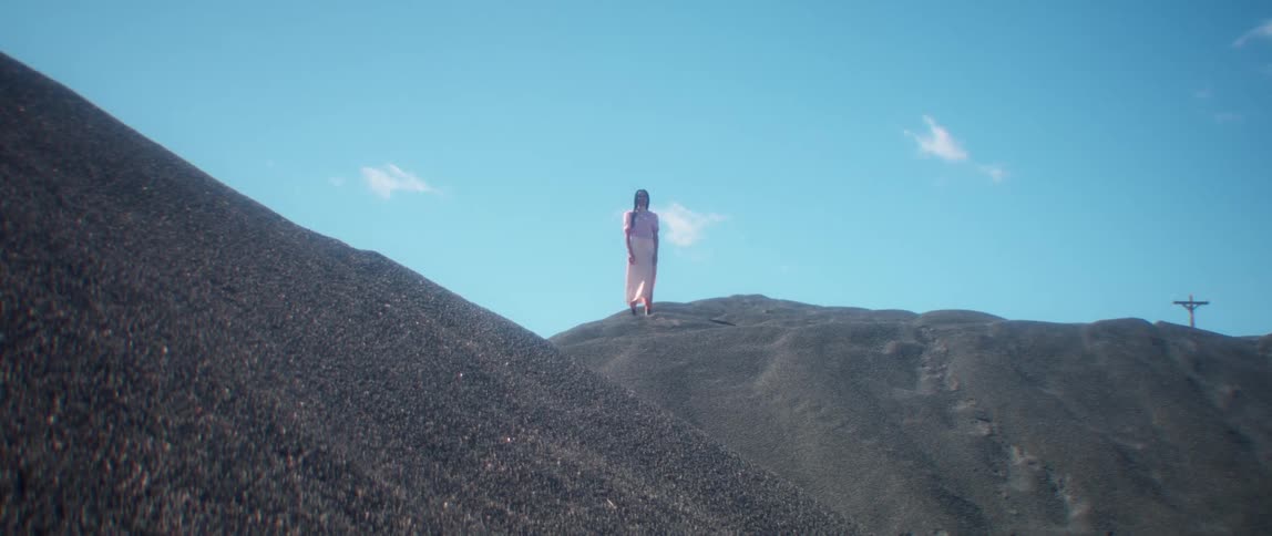 A person standing on a hill with the sky and clouds in the background