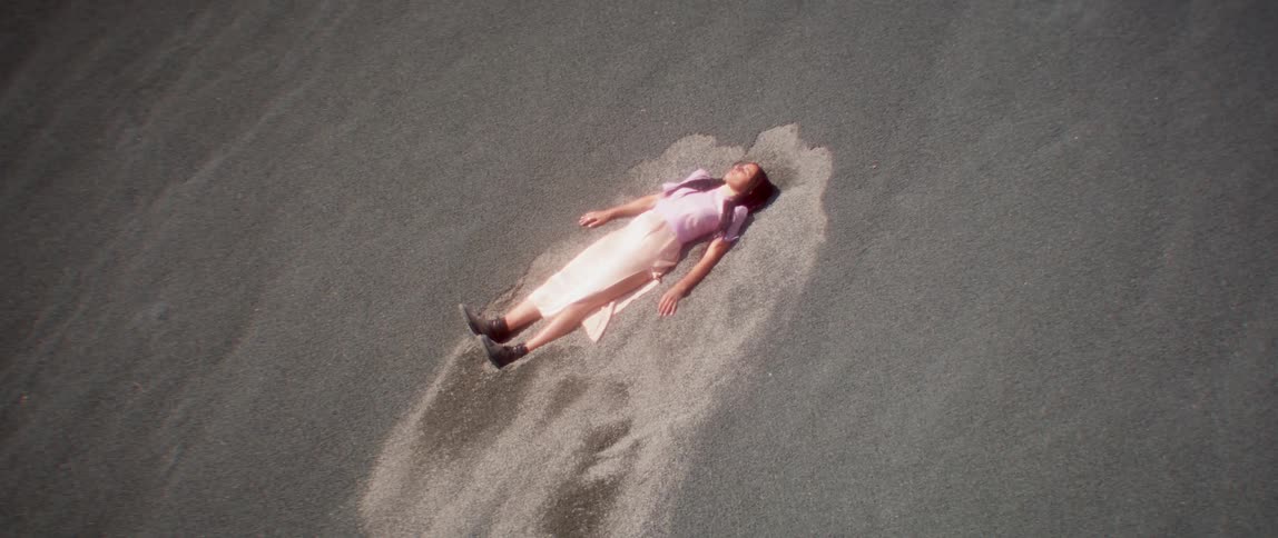A woman is laying in the sand at a beach