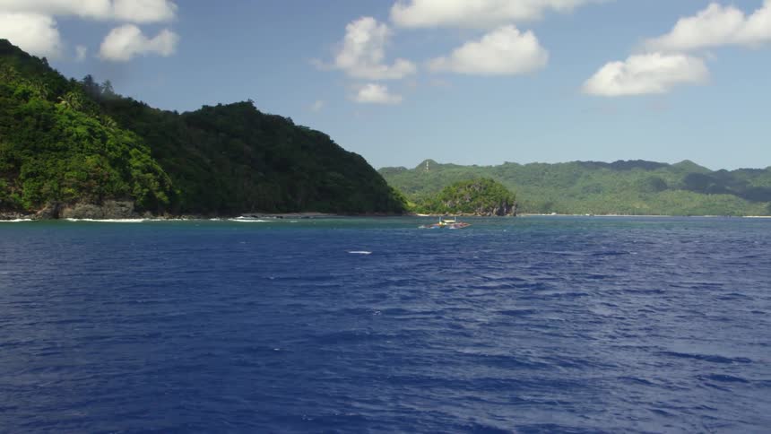 A large body of water with green mountains around it on a sunny day