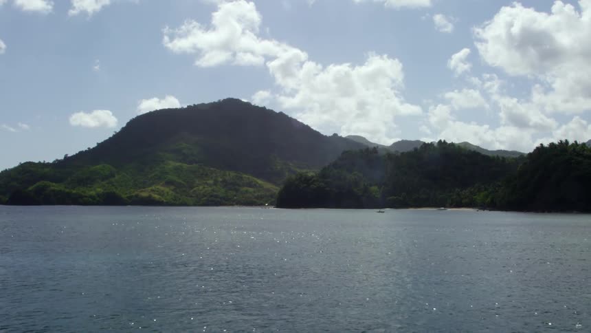 A large body of water with mountains behind it and white clouds in the sky