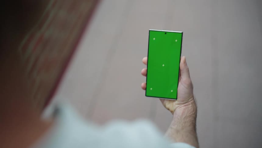 Man walks along sidewalk viewing smartphone