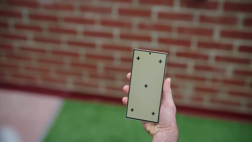 A mans hand holding a smartphone while walking toward a wall