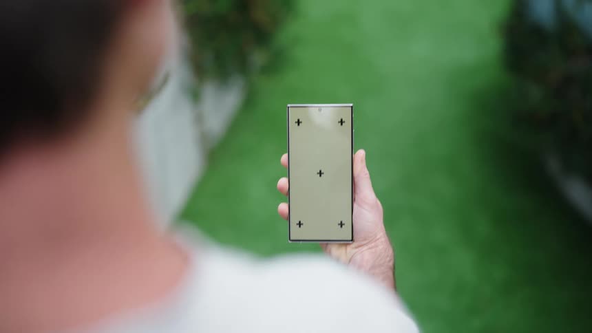 Man walks between plant beds while viewing smartphone