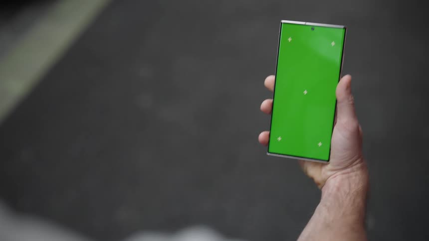 Man walks along street while viewing smartphone