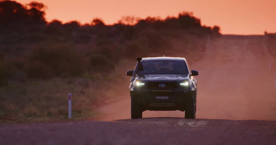 A car driving on the dirt road at sunset