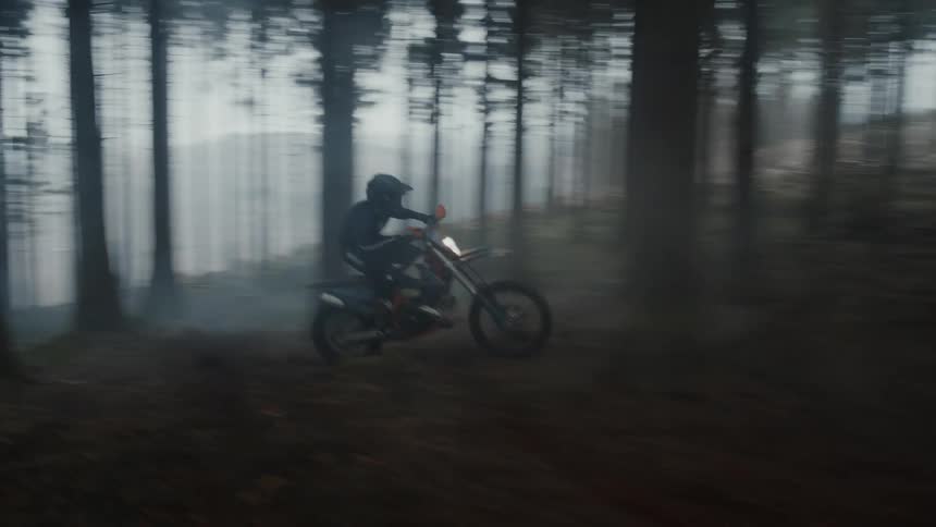 Man rides a motorcycle in the woods at sunset