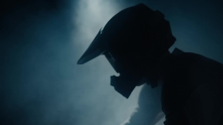 A man wearing a helmet and riding a motorcycle in a smoky environment