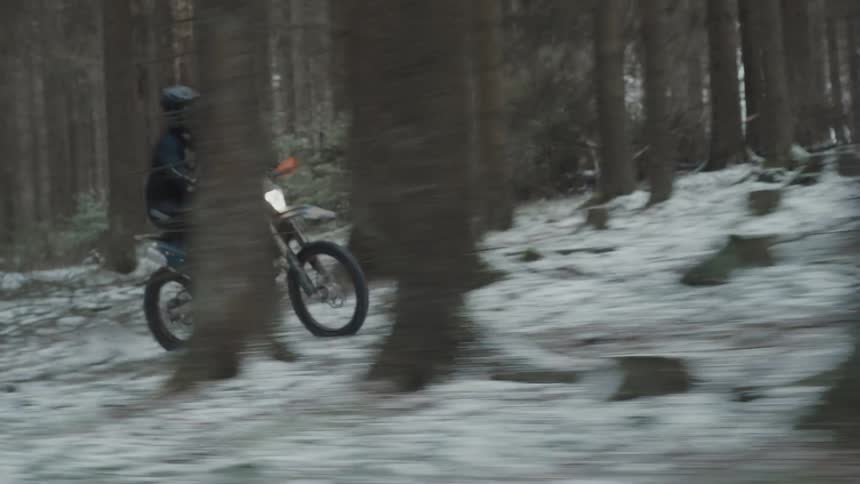 A man is racing through the forest on his dirt bike
