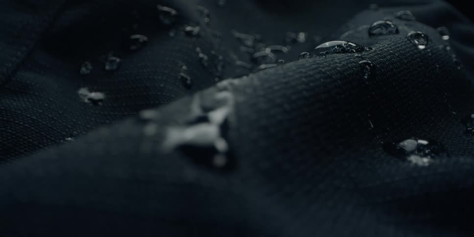 Water droplets on a dark textured surface jiggle and move as the surface vibrates