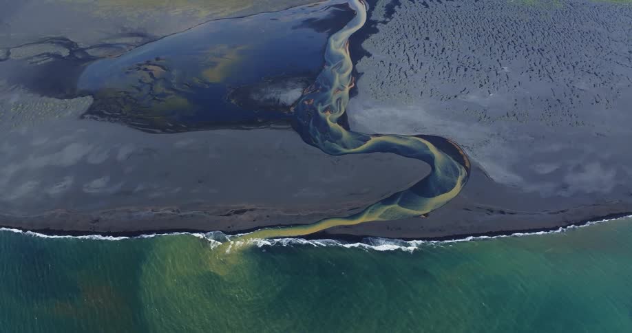 A colorful river on the black sand beach