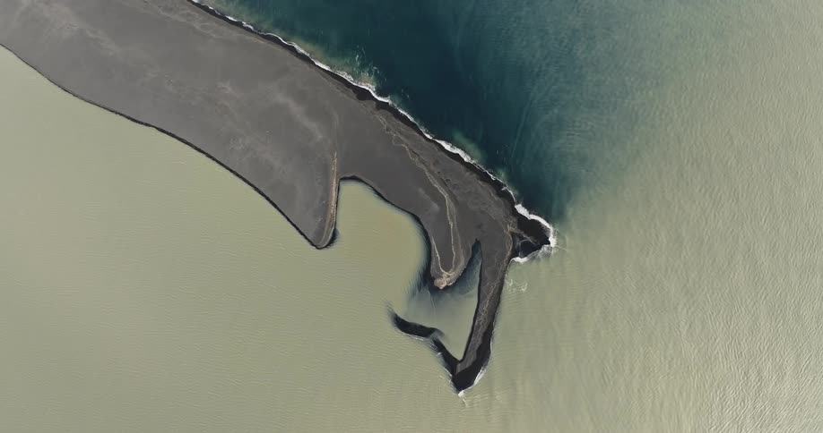 Aerial of an island in the middle of the ocean with dark sand