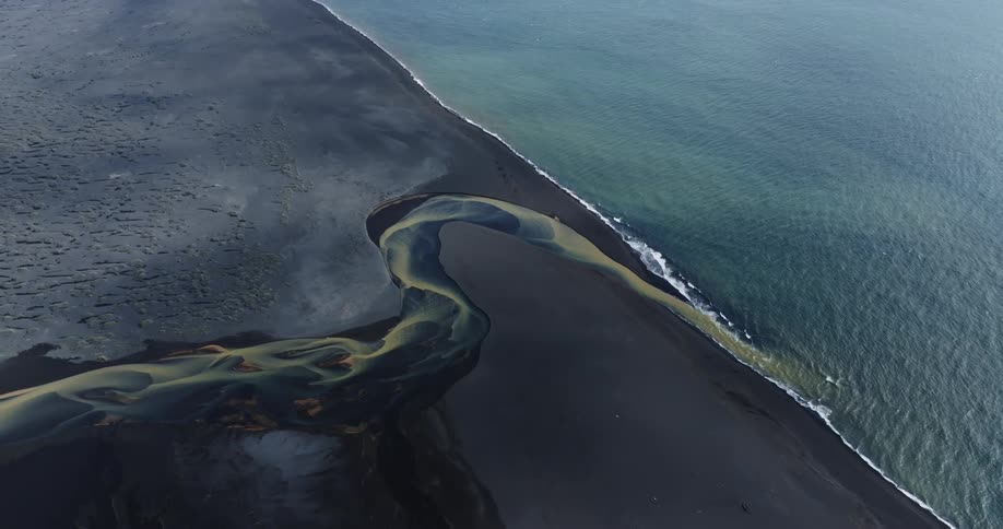 Aerial view of a blue and yellow river meeting the ocean