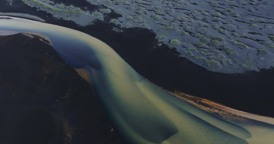 A colorful river on the black sand beach