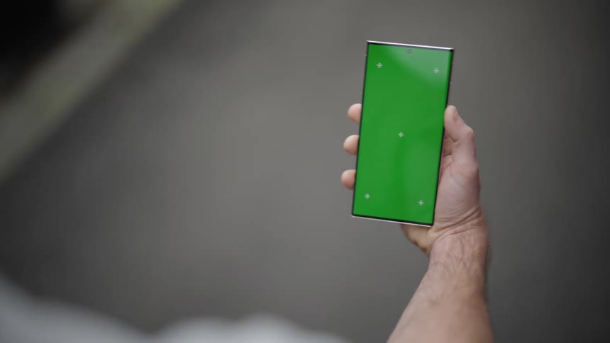 Man holds a mobile phone while walking indoor at midday