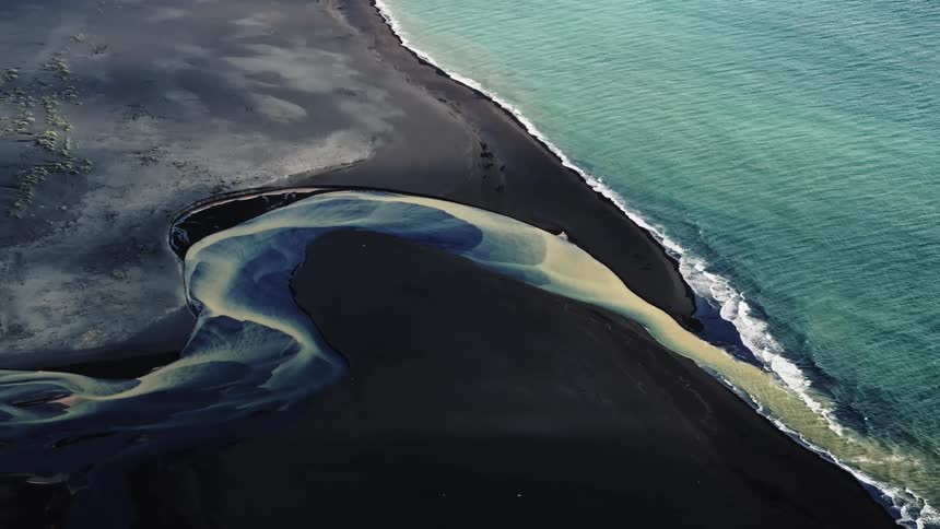 Aerial view of a blue and yellow river meeting the ocean