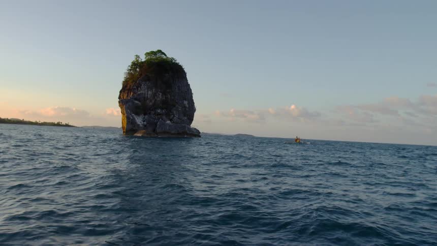 A tall rock in the middle of a body of water