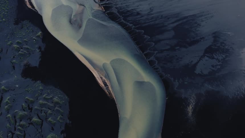 Smooth silvery mass contrasts with flat and textured surfaces bordering it