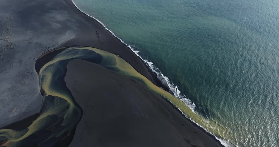 Aerial view of a blue and yellow river meeting the ocean