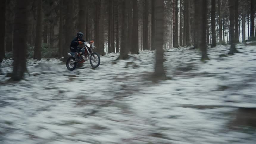 A person riding a motorcycle in the snowy forest
