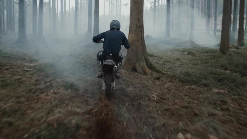Person riding a motorcycle in a muddy foggy forest
