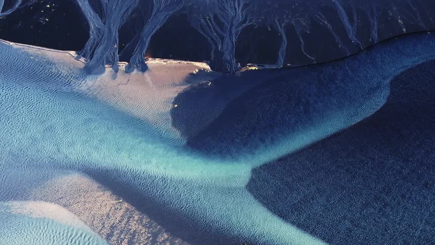 A colorful blue river on the black sand beach