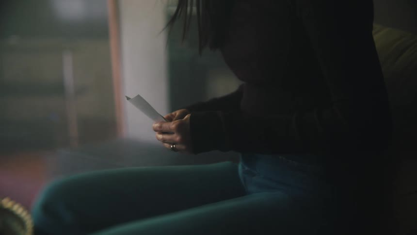 A woman is sitting down looking at receipts in her hands