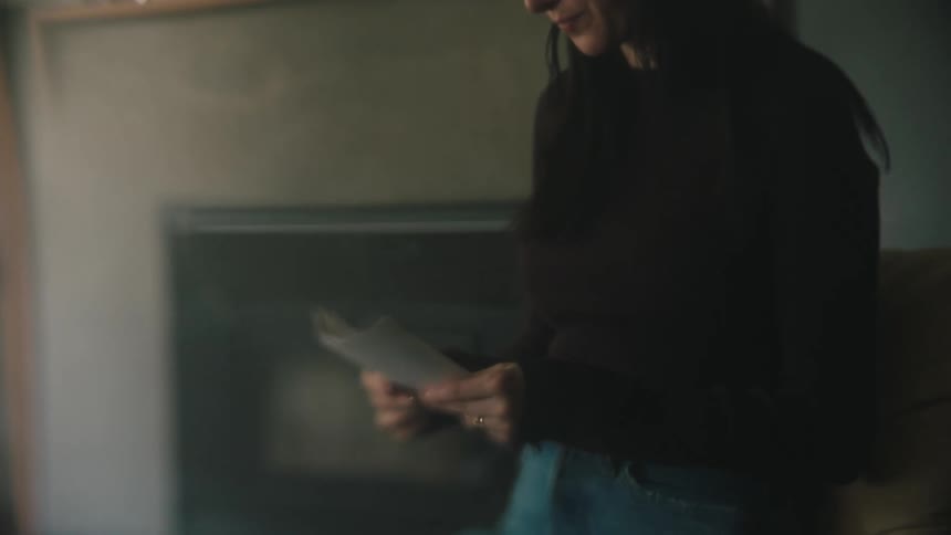 A woman is sitting down looking at receipts in her hands