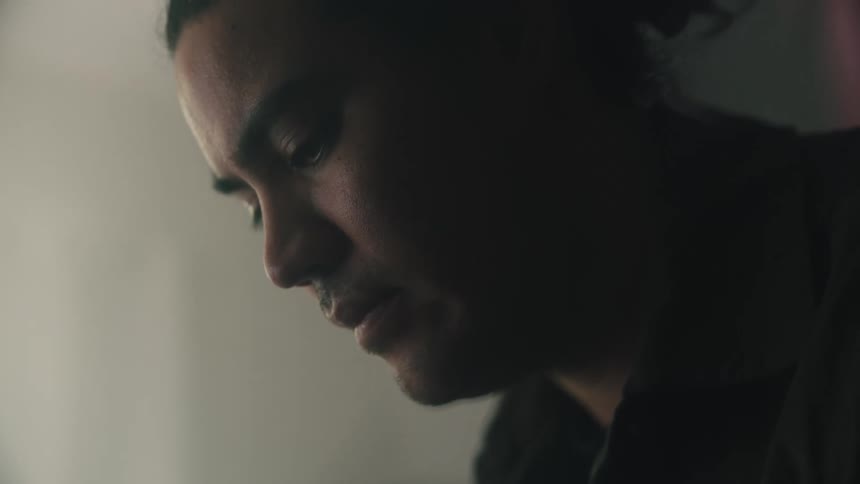 A man with a shaved beards sitting indoor with his eyes focused on something