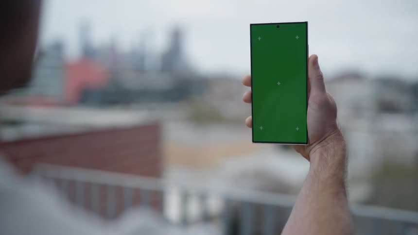 Man holds smartphone in front of himself while walking through city