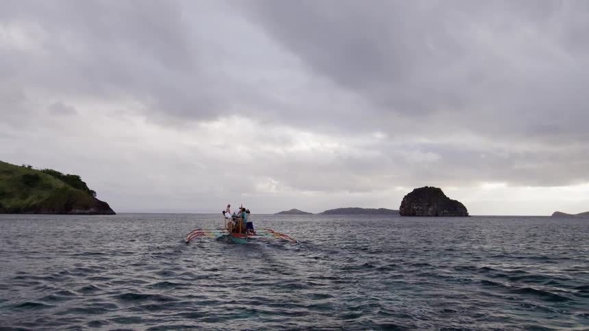 A boat full of standing people glides across the water
