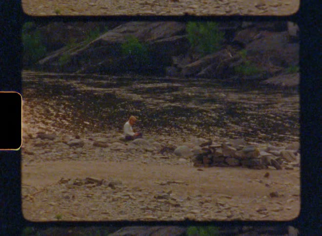 A person is sitting by the river