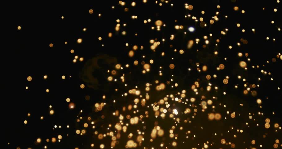 A stream of gold particles flowing and bursting across the darkness