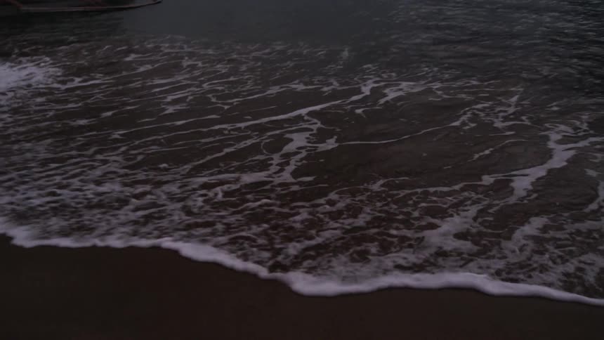 Waves crashing into shore at sunset