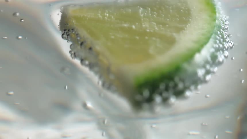 A wedge of lime floats across the surface of some sparkling water