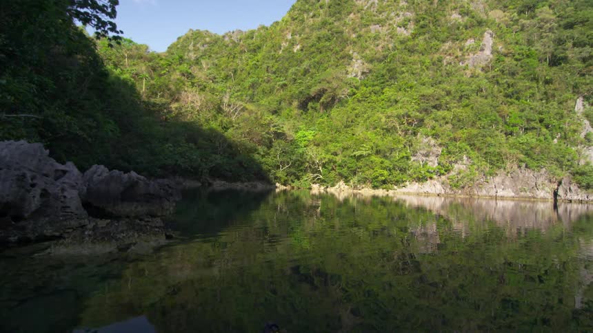 A lake leads to a mountain covered with bushes and grass